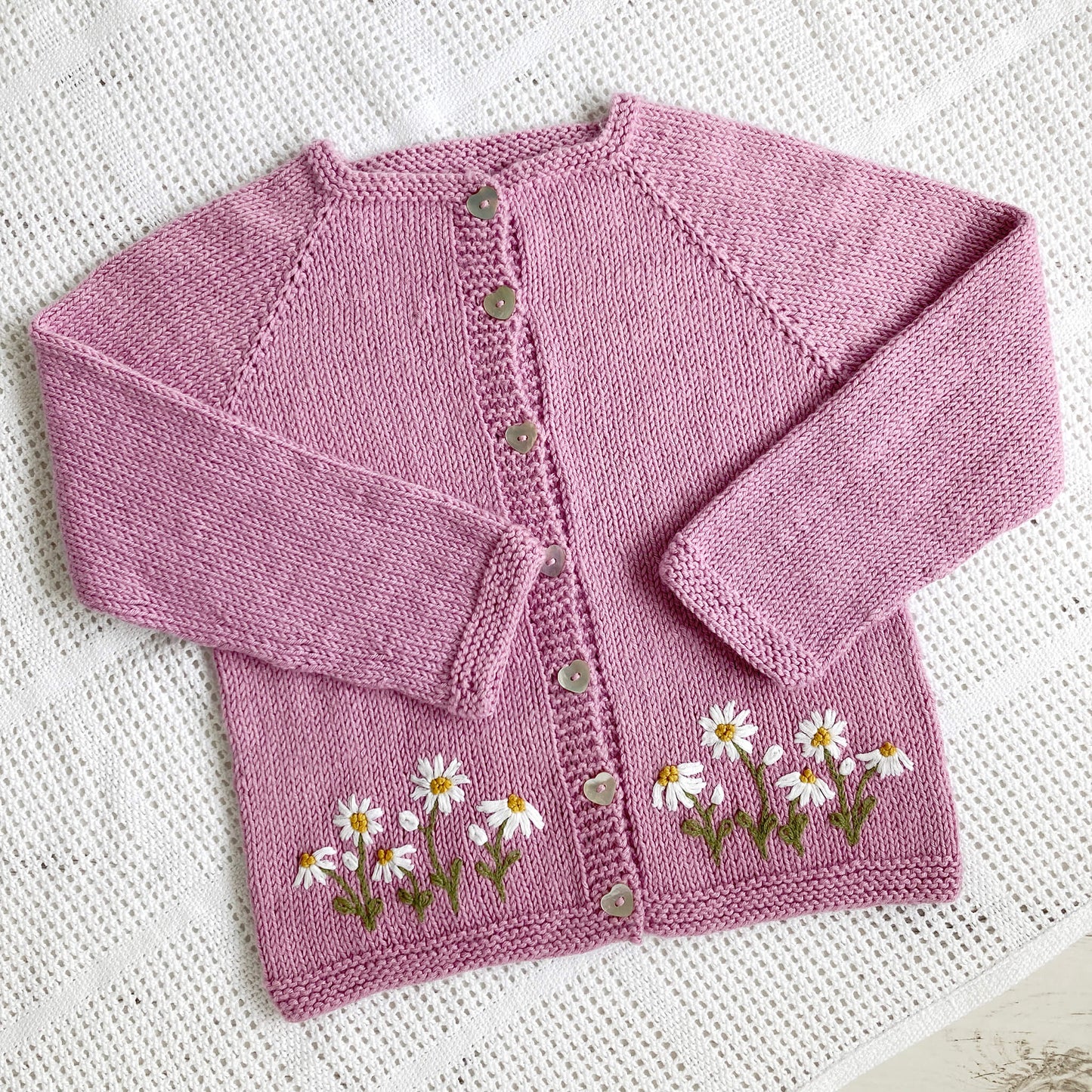 a pdf embroidery pattern for daisies. sample shows daisy embroidery on the front of a baby cardigan