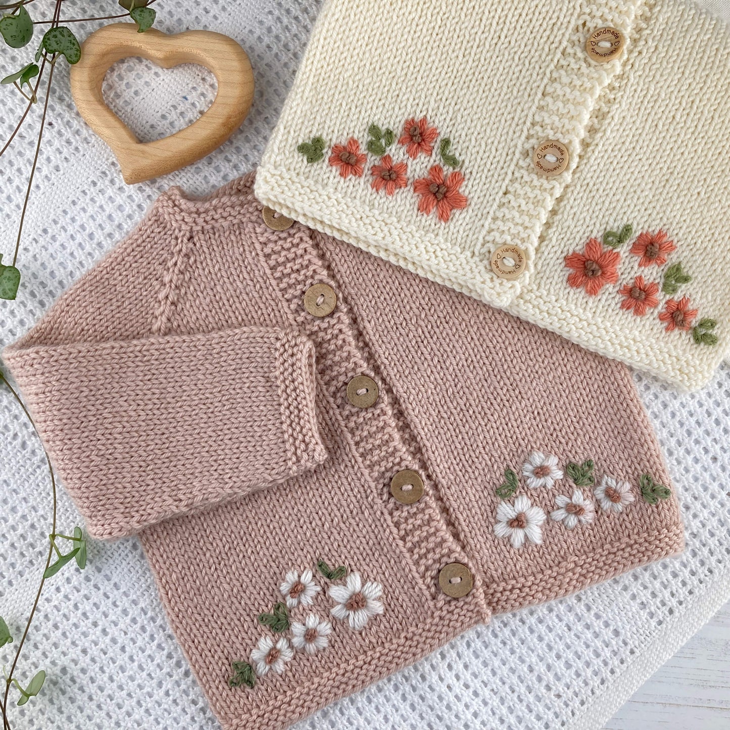 baby cardigan knitting pattern with floral embroidery on a white blanket