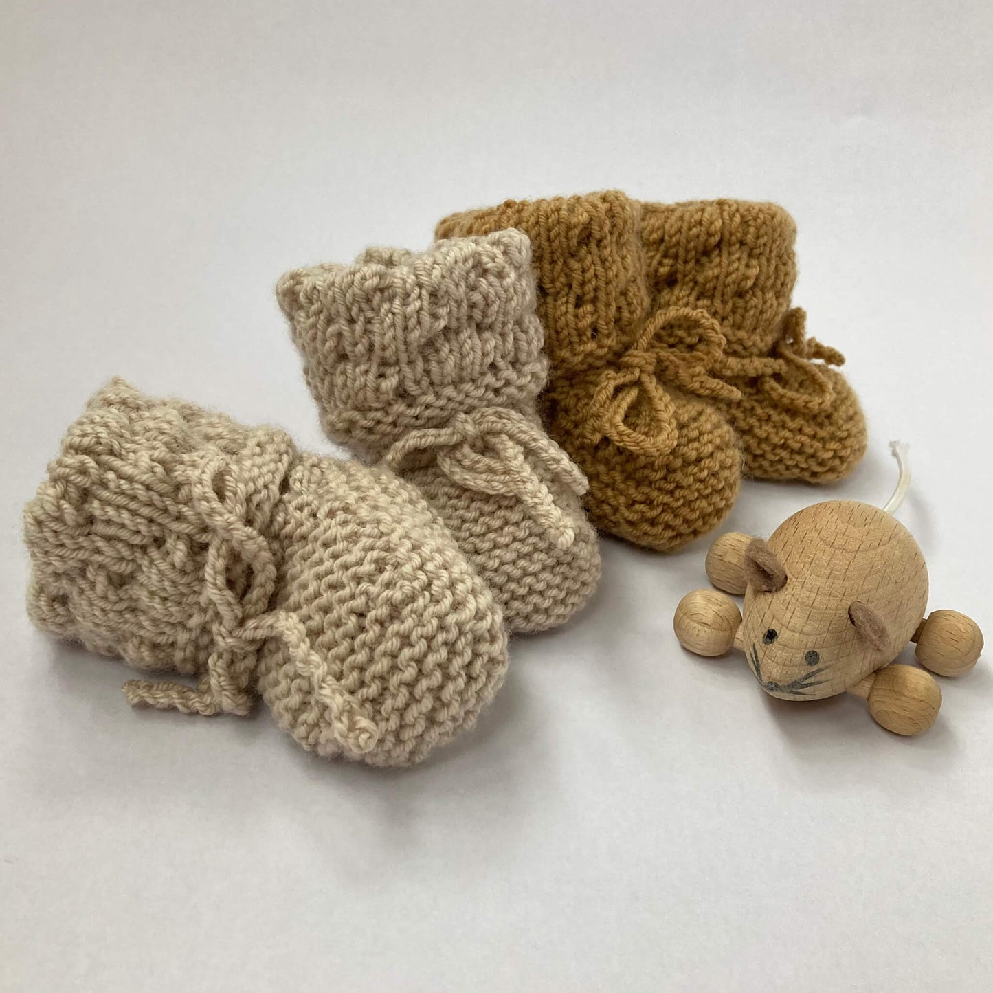 a knit pattern for booties in bubble stitch. Two pairs of booties are shown alongside a wooden toy mouse