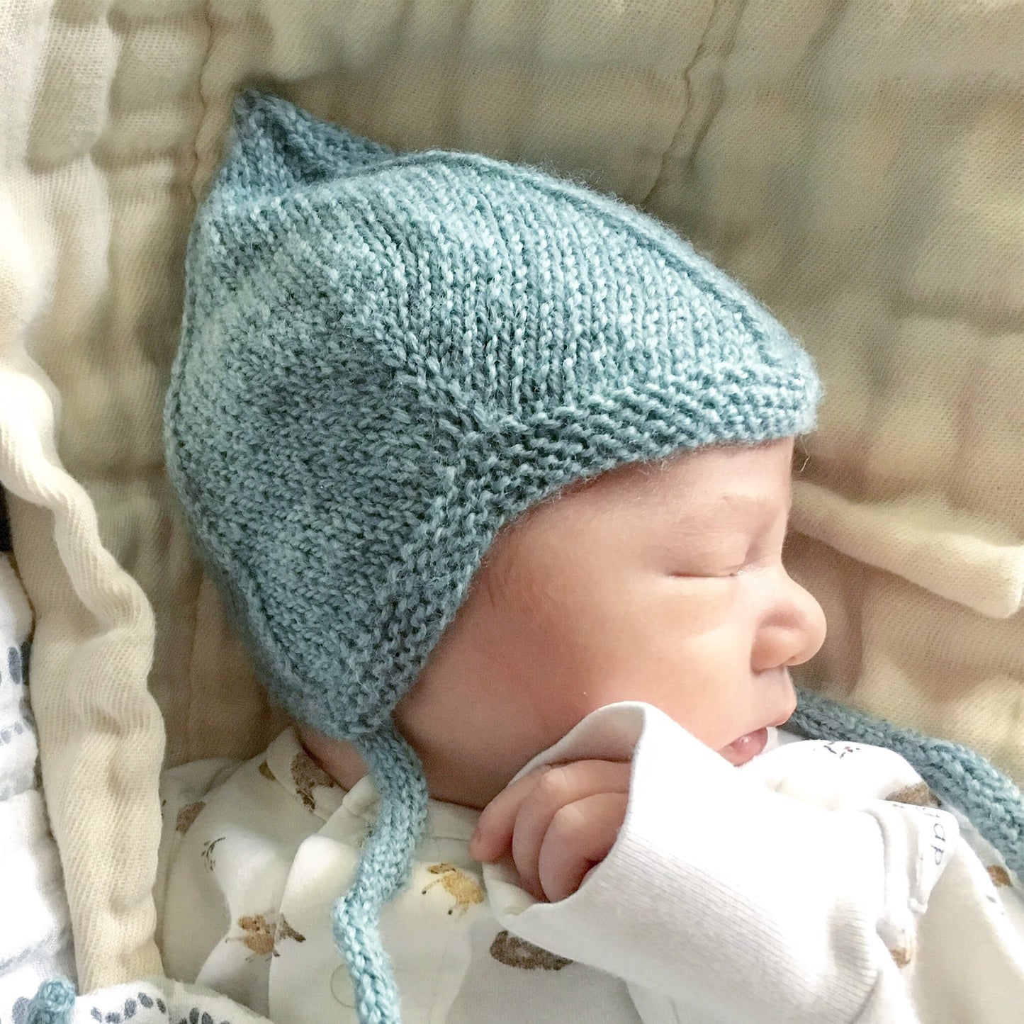 knitting pattern for a vintage style pixie hat modelled by a sleeping newborn baby