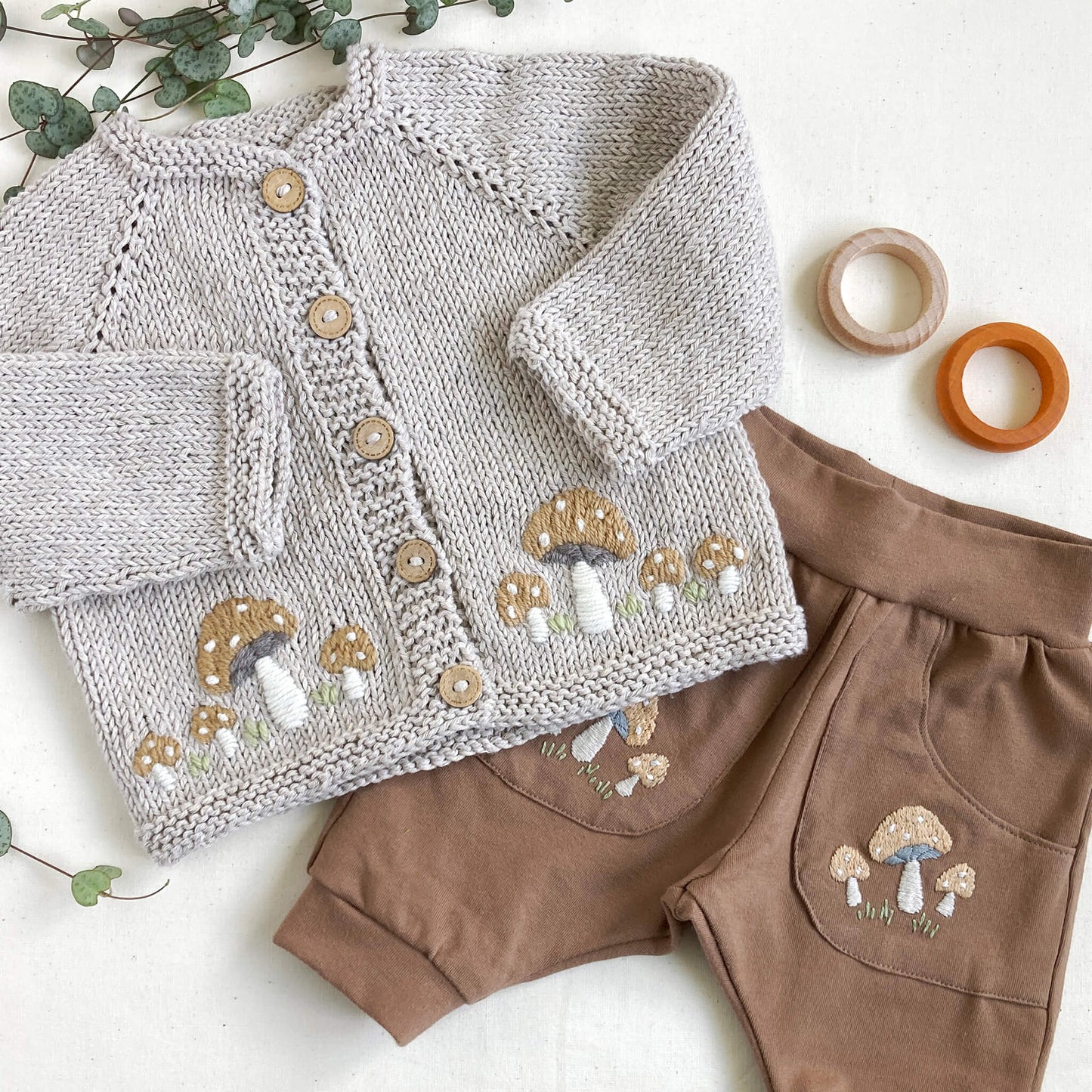 a hand embroidery pattern for toadstools for baby clothing. samples shown are toadstool embroidery on a cardigan and trousers