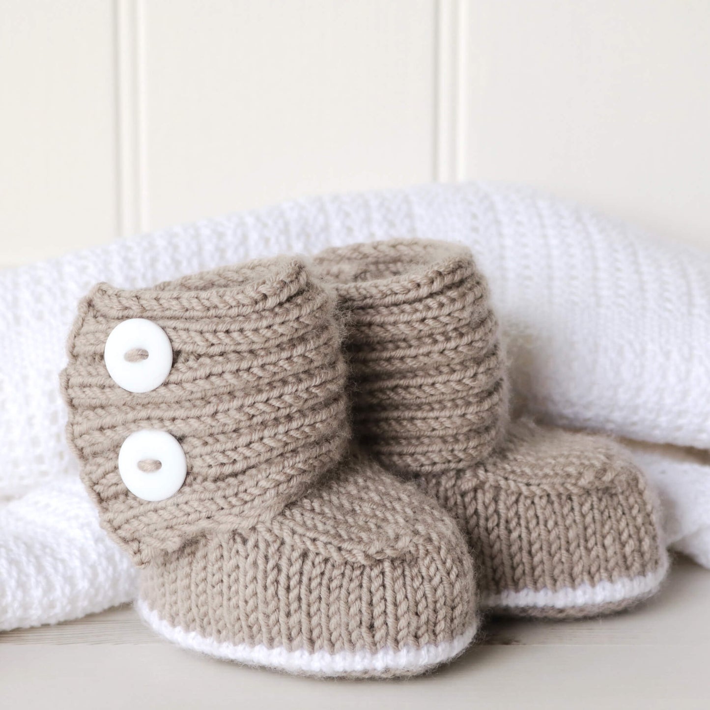 a baby booties knit pattern shown against  white blankt and wall