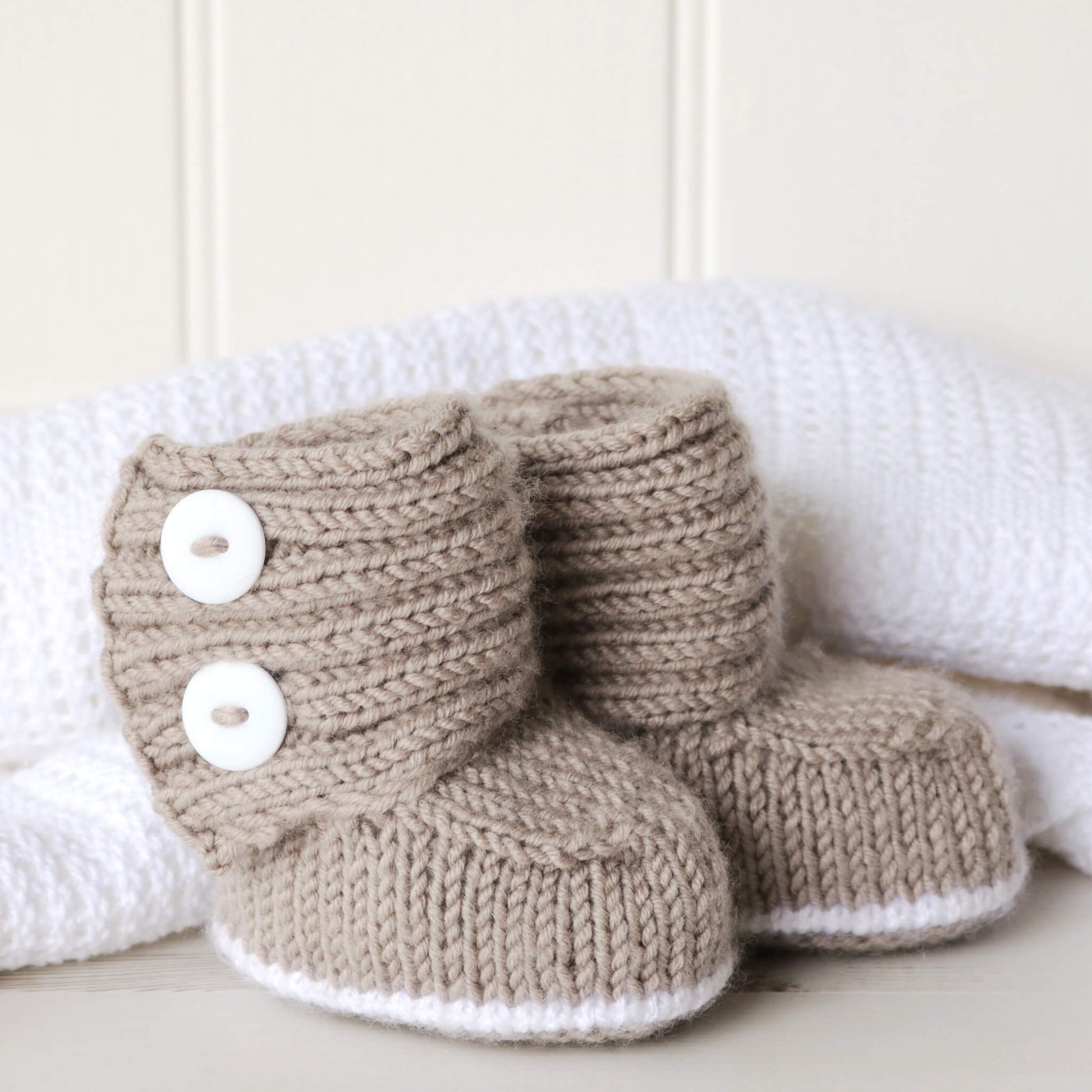 a baby booties knit pattern shown against  white blankt and wall