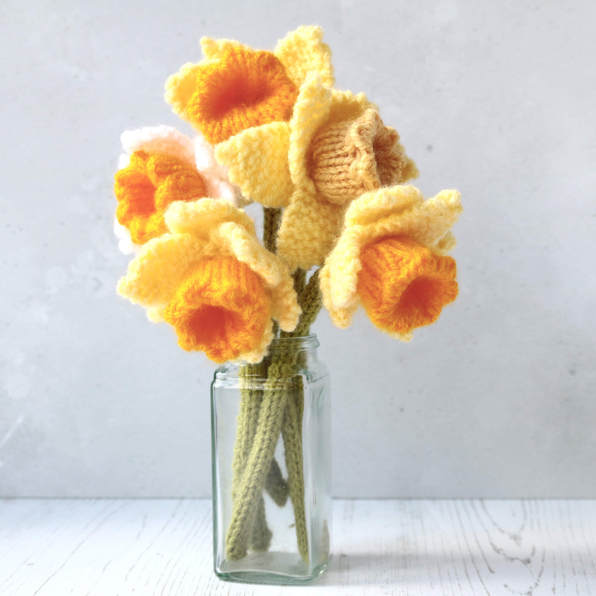 a daffodils knitting pattern. five knitted daffodils are shown in a small vase