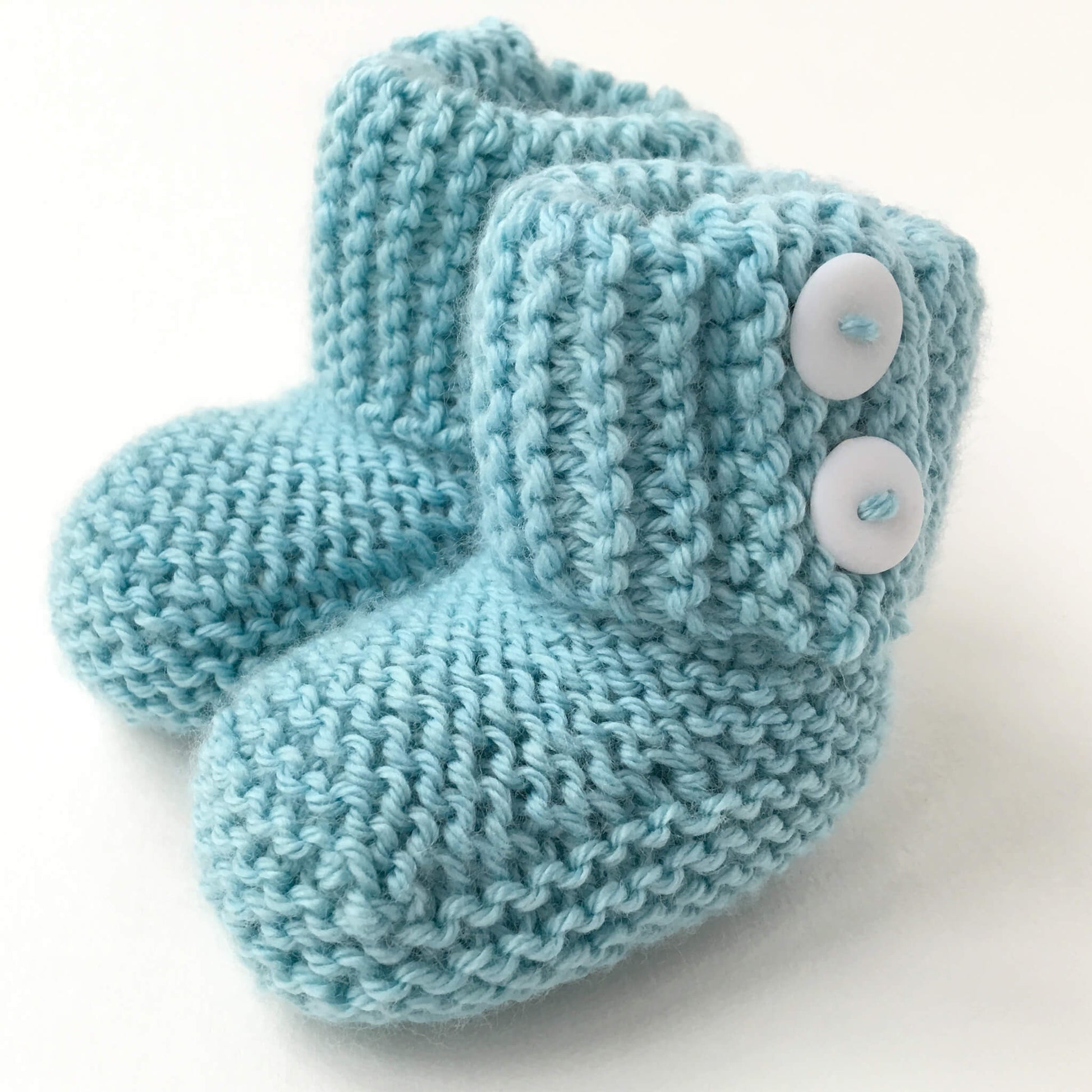 an easy baby booties knitting pattern. the booties have a fold over cuff and the sample shown are knit in turquoise yarn