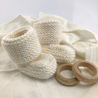 an easy knitting pattern for booties. the booties are knit in white yarn and styled on a baby blanket