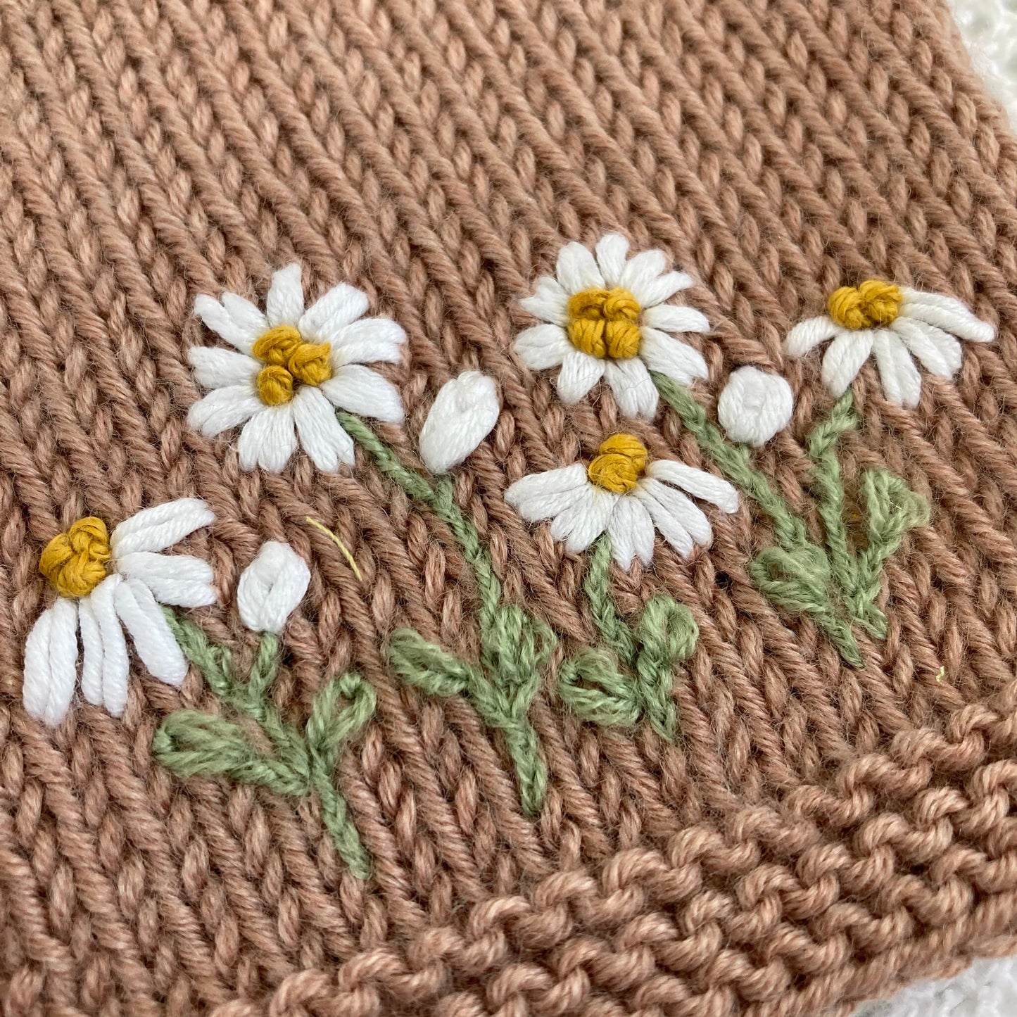 a close up photo of hand embroidery from a daisy embroidery pattern for baby clothing