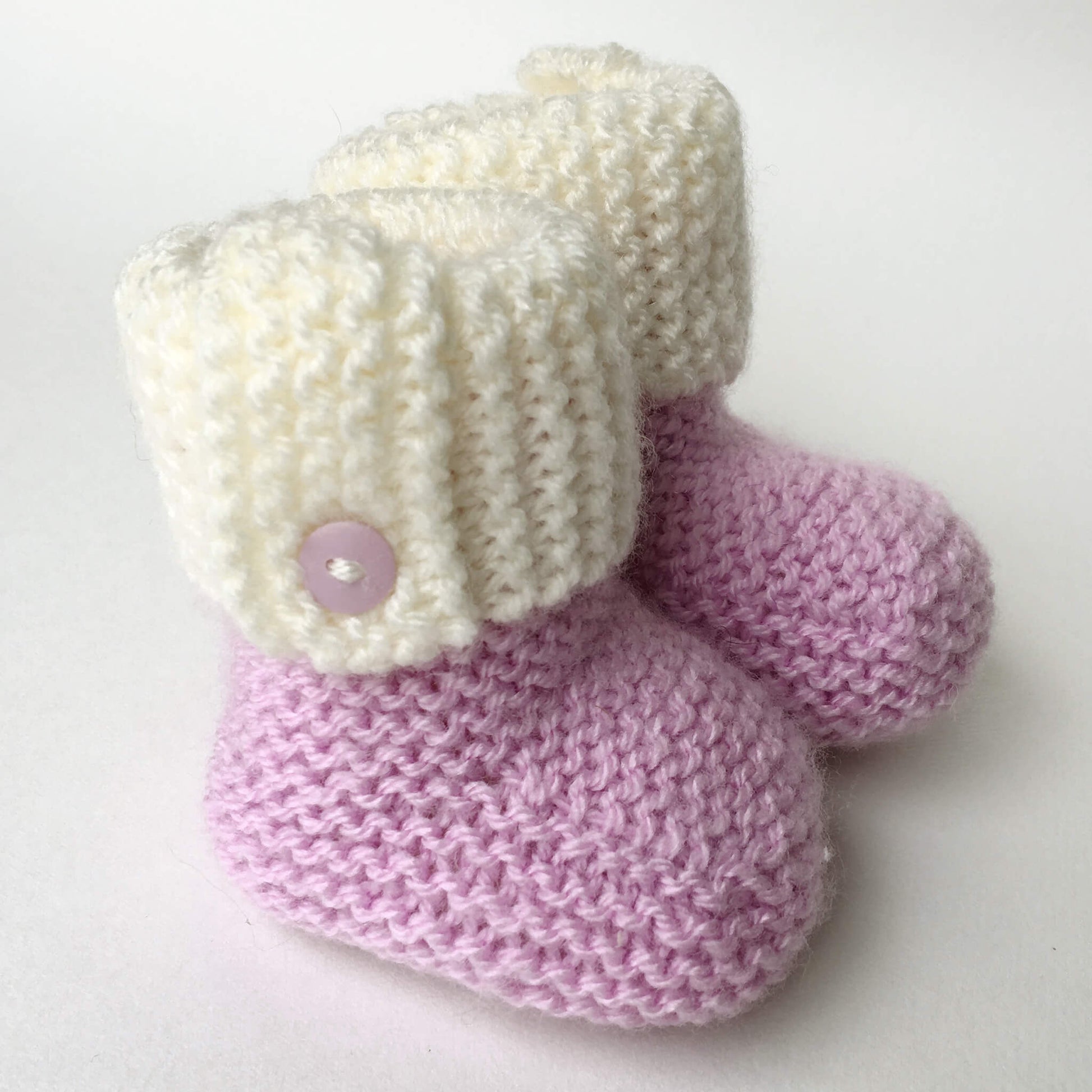 a booties knitting pattern shown with a pink  foot section and a white cuff