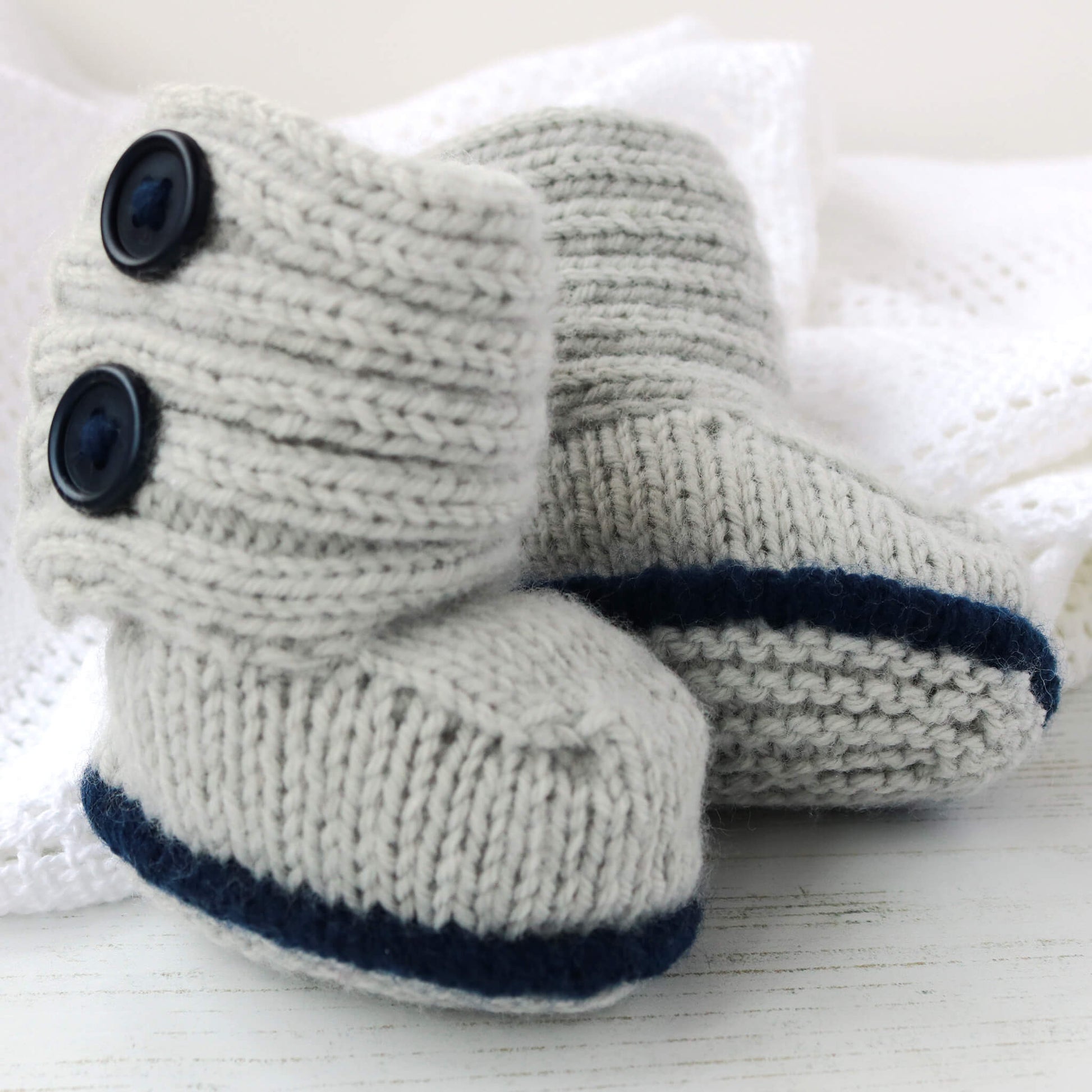 modern baby booties knitting pattern shown in light grey and navy