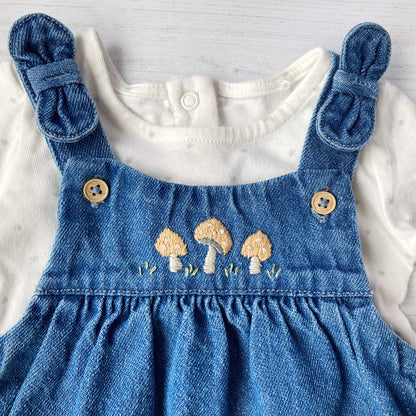 toadstool embroidery pattern  for baby clothing. toadstool embroidery is shown on the yoke of a denim pinafore dress